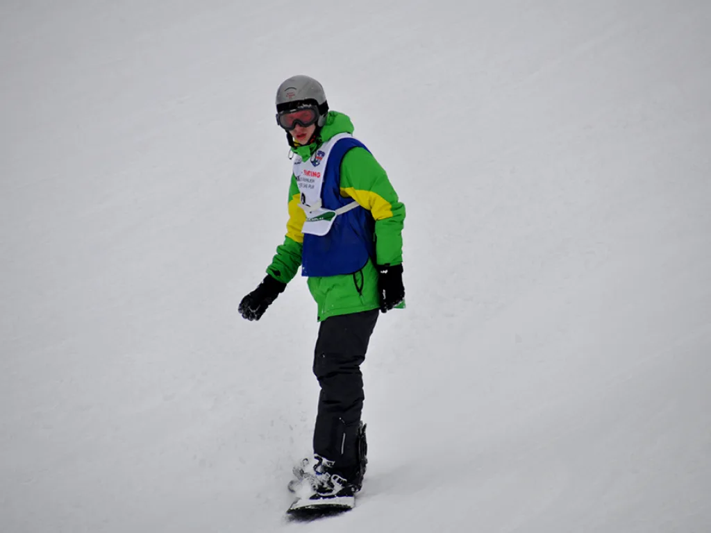 Snowboarder in grüner Jacke auf der Rennstrecke.